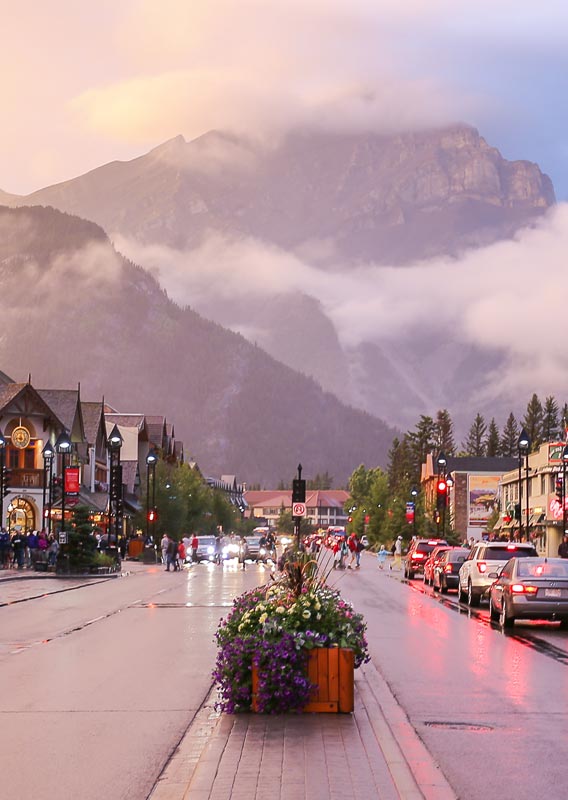 A view down a street towards a tall mountain, surrounded by misty rain clouds