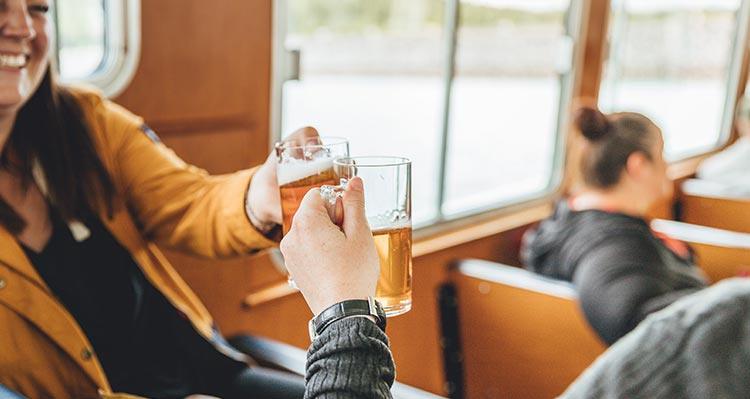 Two people raise their glasses of beer in a cheers.