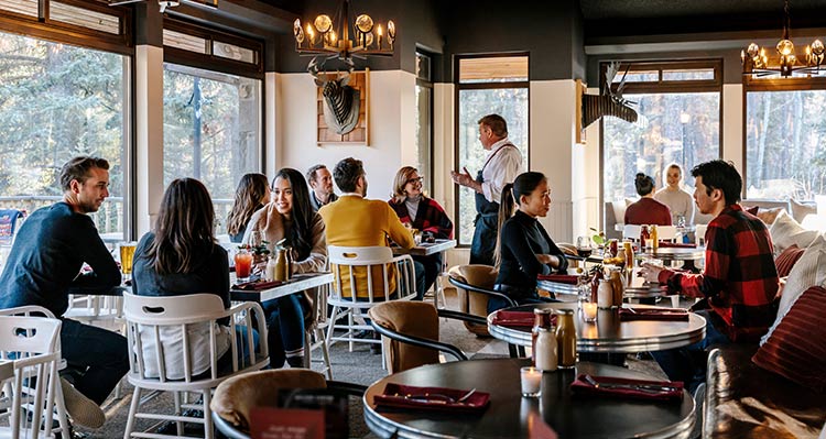 Groups of people sit at tables at the Maligne Canyon Wilderness Kitchen