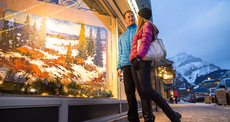 Two people window shop along Banff Ave.