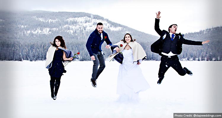 A wedding party jumps in the snow.