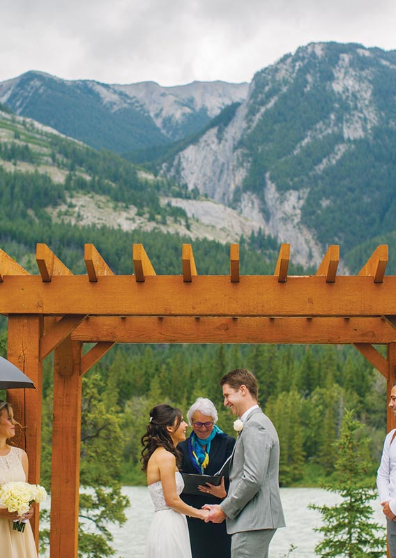 A wedding ceremony below a wooden archway.