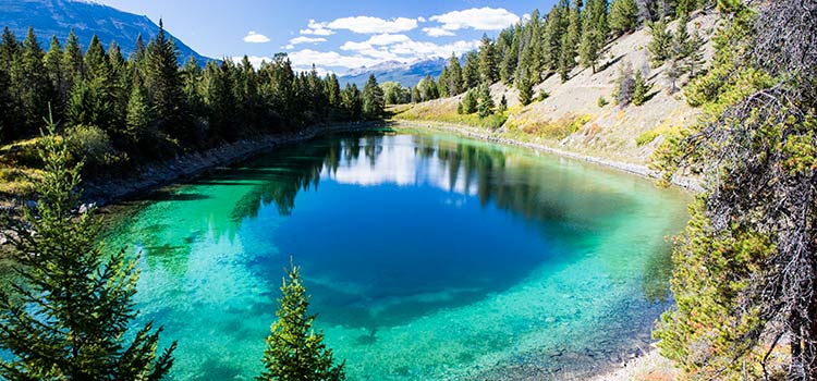 A pristine lake with blue and green hues with mountains in the distance