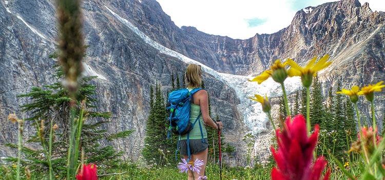 A female hiker on a trail observing a glacier set in the mountains