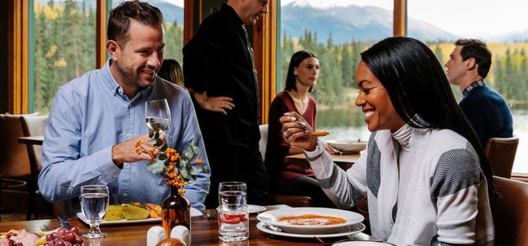 A couple sits at a table sharing food and wine