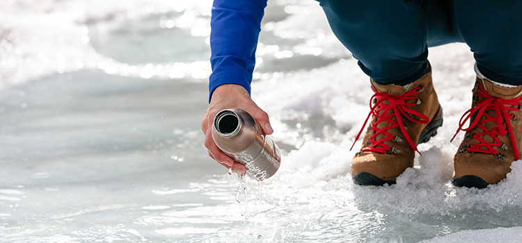 A person holds a water bottle next to ice