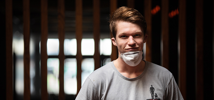 A volunteer smiles with a face mask pulled down