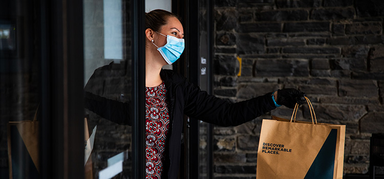 a woman with gloves bagging potatoes in a to-go bag