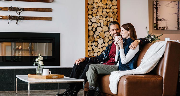 Two people sit in a lounge near a fireplace.