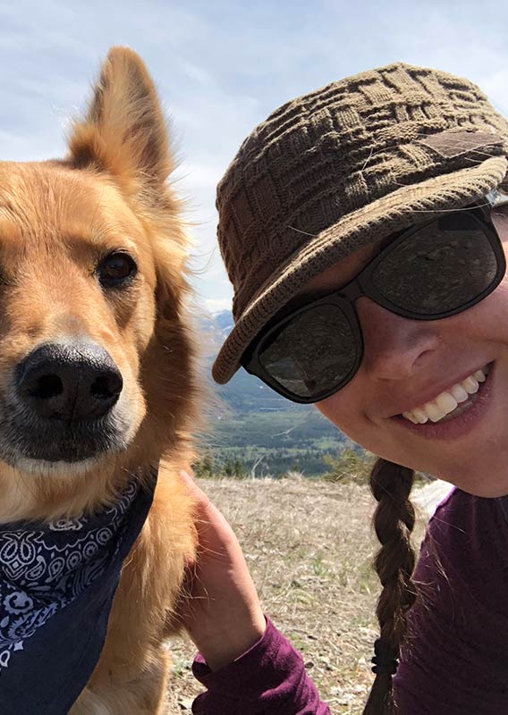 A woman and a dog at the top of a mountain.