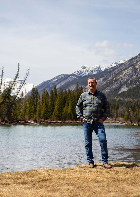 A man stands on a riverside.