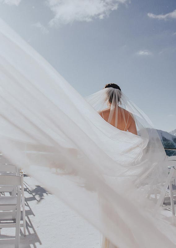 A bride walks at on a balcony overlooking a mountain valley.