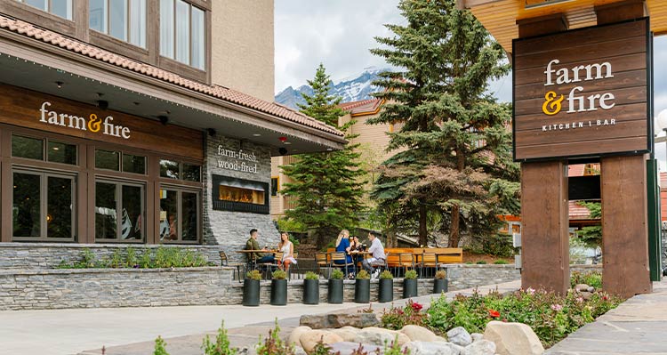 A restaurant patio below a wooden sign.