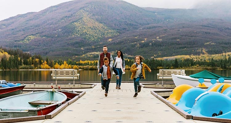 A family walks and runs along a dock.