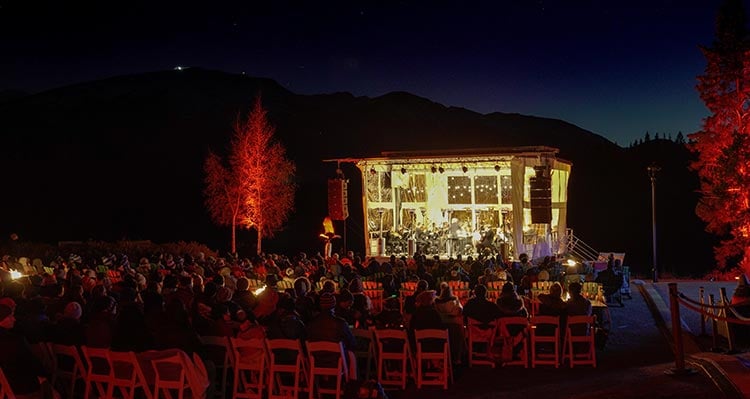 A concert performance on a stage below a dark night sky.