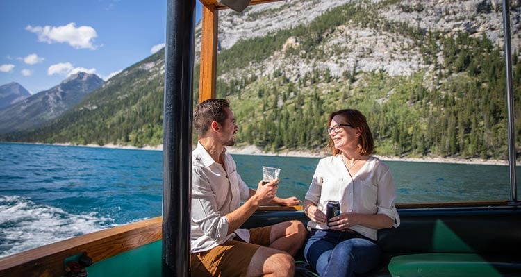 Two people sit at the back of a boat on the water.