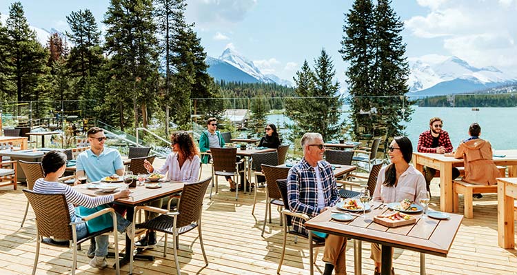 Tables set on a deck above a lakefront.