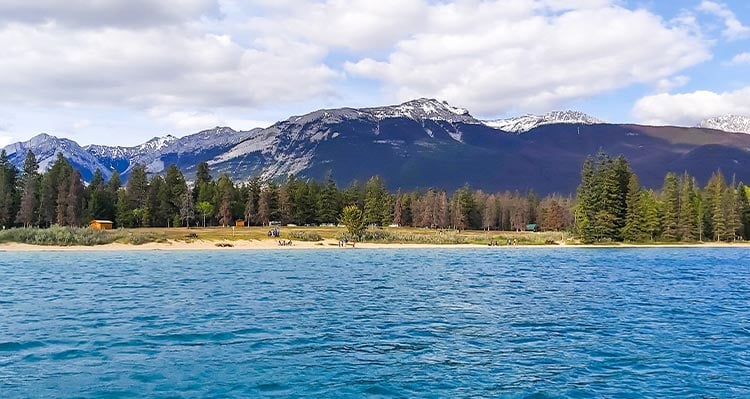 A blue lake below forested mountains.