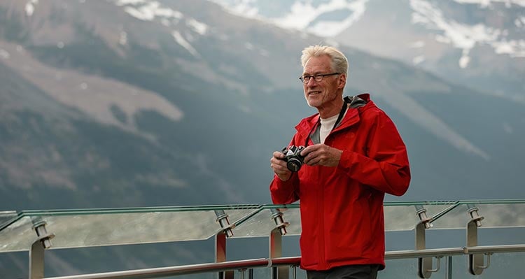 A man stands at a railing with a camera, ready to take a photo.