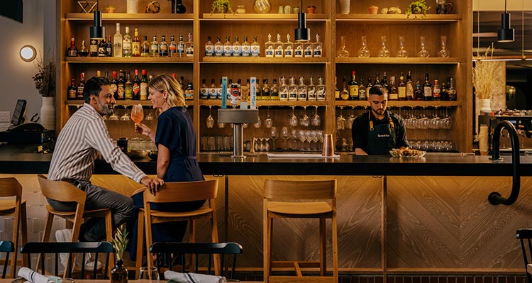 Two people sit at a restaurant bar.