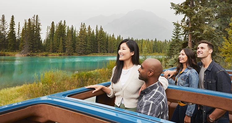 A group of people stand out from the top of an open-roofed automobile.