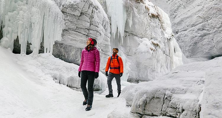 Two people walk through a frozen canyon.