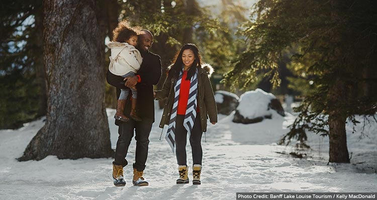 A family walks through a snowy forest.