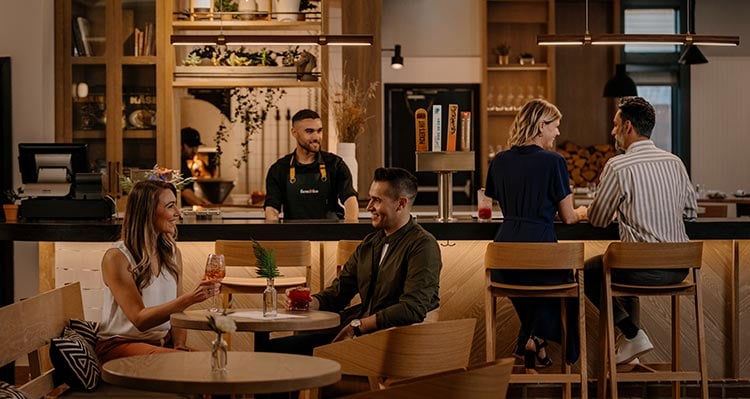 Groups of people sit at tables in a restaurant dining room.