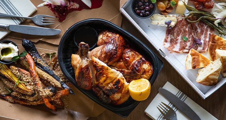 A rotisserie chicken dinner in a takeout contianer.