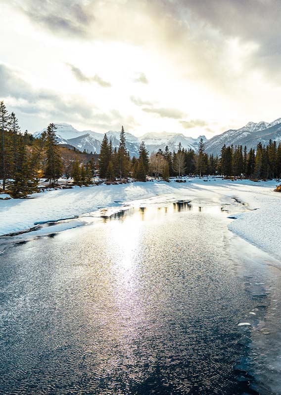 A view across a frozen river between tree-lined shores.