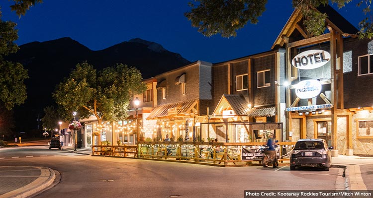 A view down a small town main street, with hotels and restaurants lit up.