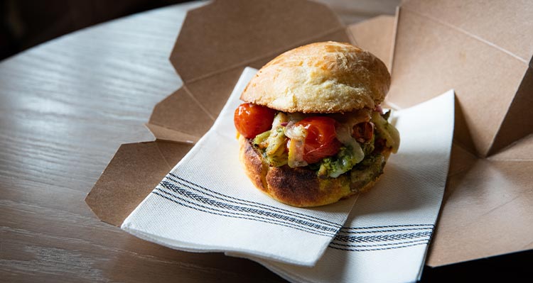 A sandwich in an open takeout box.