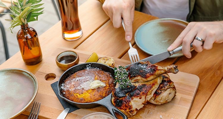 A man cuts into chicken on a restaurant table