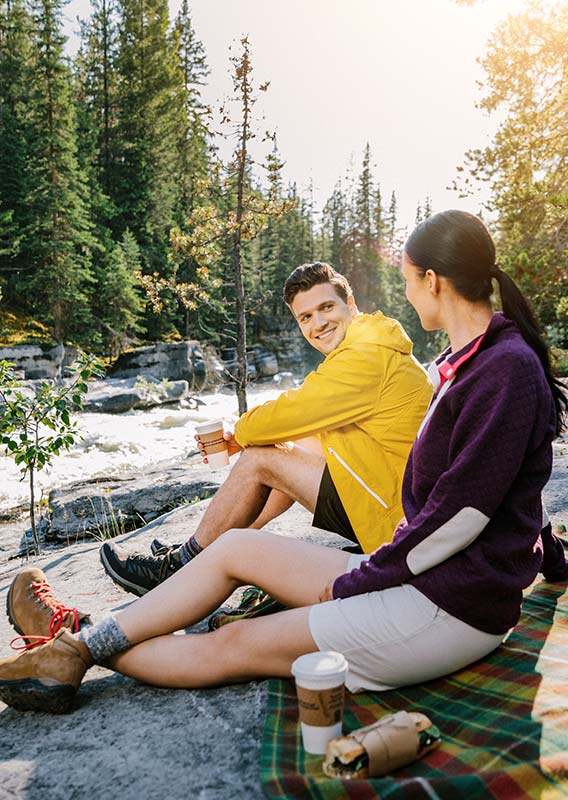 Two people stand at a viewpoint over a rocky canyon.