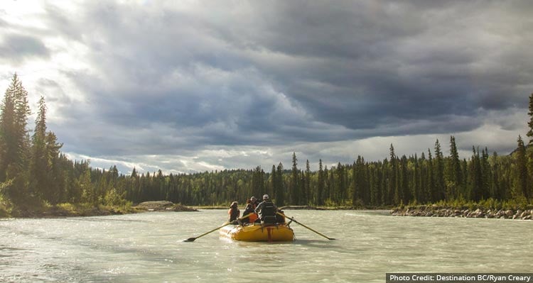 A rafting tour group floats down the middle of a river.