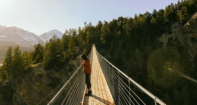 A girl leans at the railing of the suspension bridge.