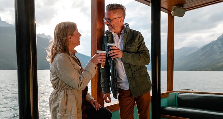 A couple enjoys a beverage on the boat at sunset.