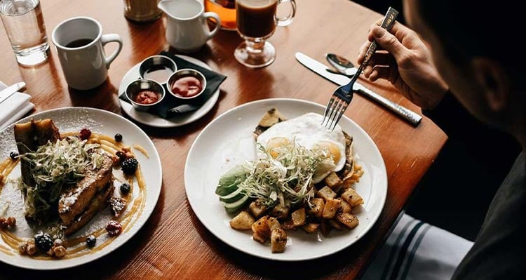 Breakfast plates of of French toast, eggs and potatoes.