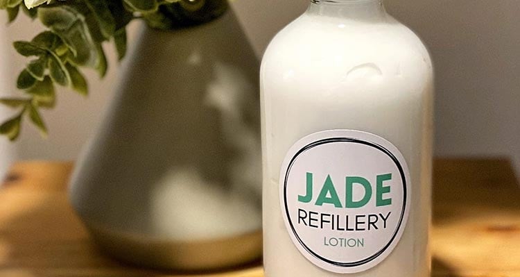 A bottle filled with lotion and a Jade Refillery logo on it.