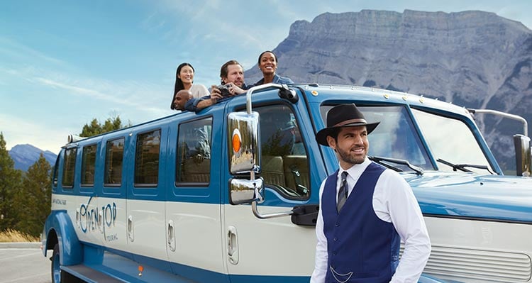 A group of people peer out of the top of the vehicle