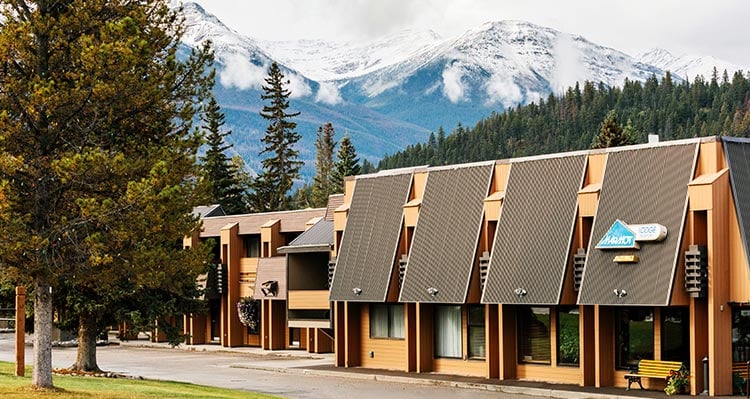 A hotel building with Marmot Lodge signage and snowy mountains behind.