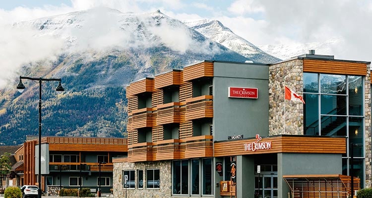 Hotel exterior of The Crimson Hotel, with snowy mountains in the back.