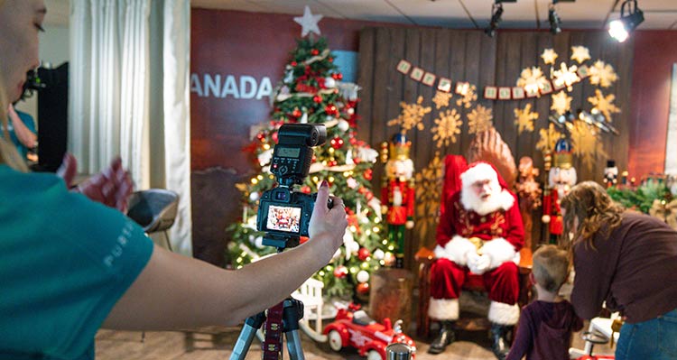 A child and mother approach Santa, a photographer waits to take a photo.