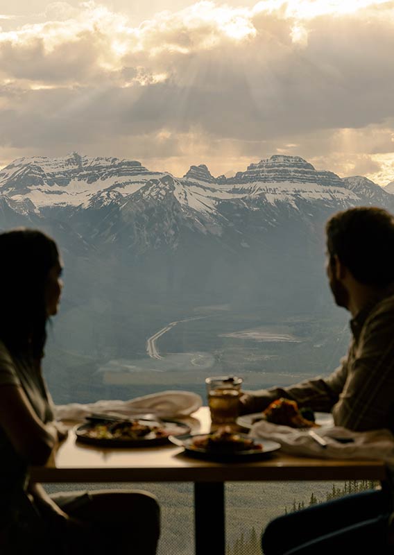 Two people look out a window to the mountains in Banff.