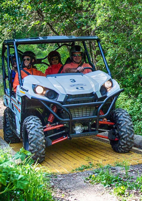 A group of people ride an ATV over a bridge