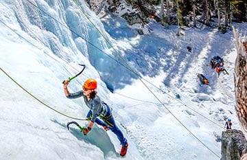 A person ice climbs on a frozen waterfall.