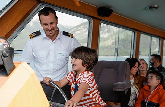 Captain watches young boy steer the cruise boat