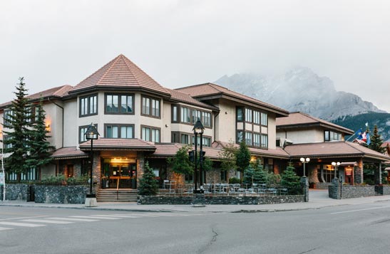 The Elk and Avenue hotel at a street intersection with mountains in the background