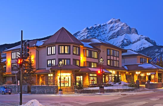 The Elk and Avenue hotel at a street intersection with mountains in the background