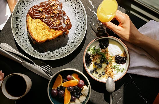 A table full of breakfast food from above including a mimosa and chocolate covered french toast.